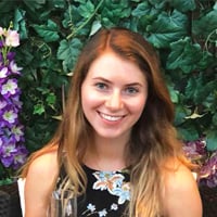 Sydney P. in a bright green garden with purple flowers.