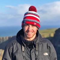 Drew L. smiling at the Cliffs of Moher with the sunsetting.