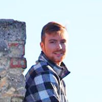 Jack A. at sitting on the gray stone wall of a castle