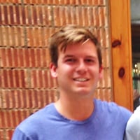 Daniel C. standing in front of red brick wall